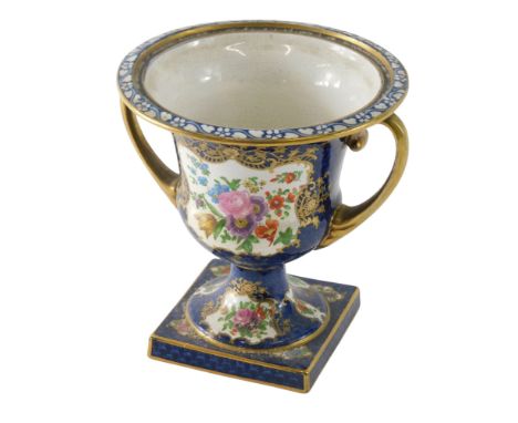 An early 20thC ceramic two handled urn, decorated with flowers, on a scaled blue ground, picked out in gilt, unmarked, possib