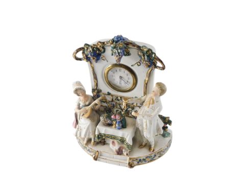 A late 19thC German porcelain clock group, modelled in the form of two figures, of a female musician, gentleman with glass, b