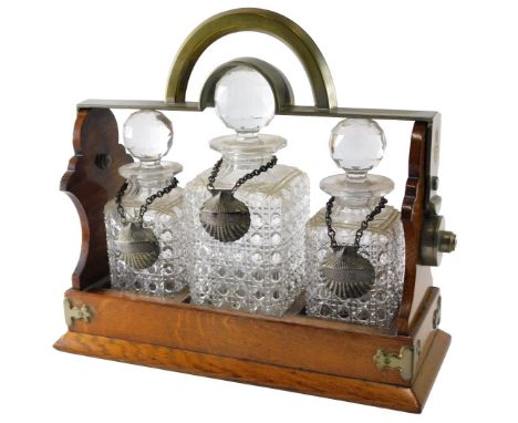 A late 19th/early 20thC Betjemann's patent oak and silver plated tantalus, the hinged top housing three square section cut gl