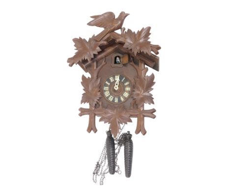 A Black Forest cuckoo clock, the case carved with a bird, leaves, etc., 40cm high. 