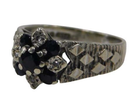 A 9ct white gold, sapphire, and diamond flower head ring, on diamond and bark effect shoulders, size M, 3.8g.