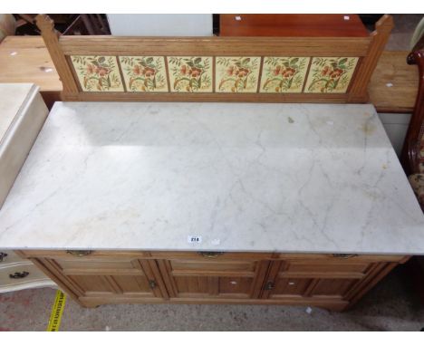 A 1.22m Edwardian oak marble topped washstand with decorative tiled splashback, three frieze drawers and triple cupboard door