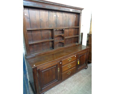 A 1.77m late Georgian oak two part dresser with fluted cornice to multi-shelf open plate rack over a base with three graduate