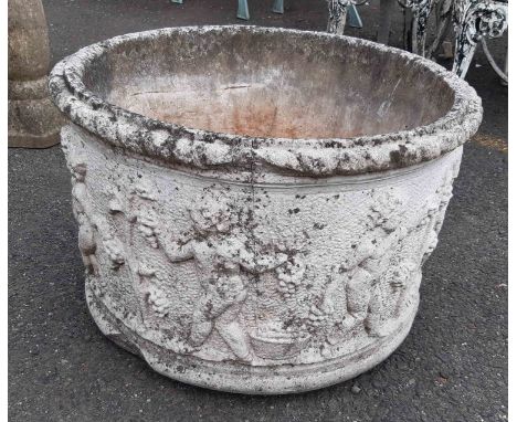 A large concrete round garden planter with classical frieze decoration