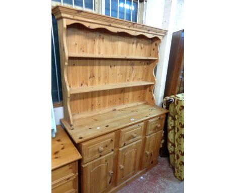 A 1.2m modern pine two part dresser with two shelf open plate rack over a base with three frieze drawers and triple cupboard 