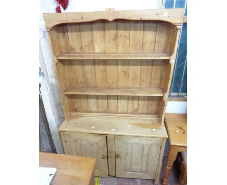 A 1.11m 20th Century waxed pine two part dresser with two shelf open plate rack over a base with pair of panelled cupboard do