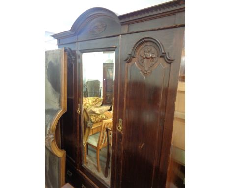 A 1.6m Edwardian stained walnut triple wardrobe with break arch cornice, central bevelled mirror panel door, flanking panelle