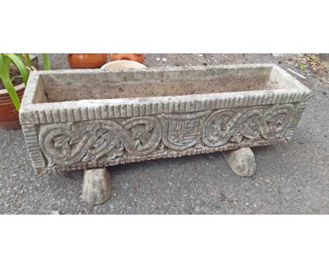 A concrete garden trough planter with armorial decoration and stands