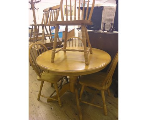 An oak kitchen table, circular top on pedestal stem and four stick-back chairs