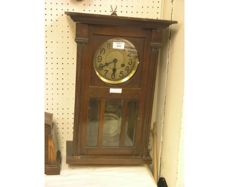 A 1920's wall clock, glazed trunk door enclosing circular dial, with key and pendulum, 20in. and an architectural walnut mirr