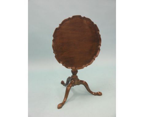 A George III-style mahogany tripod table, tilting circular top with pie-crust border, stem with twin helical beads, pad feet,