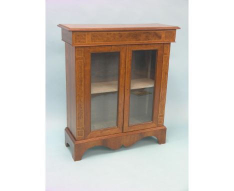 A reproduction burr elm display cabinet, pair of glazed doors enclosing lined interior with single shelf, boxwood-strung with