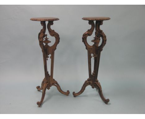 A pair of Victorian dark mahogany torcheres, each with circular top on carved and tapering scroll stem with double-scroll tri