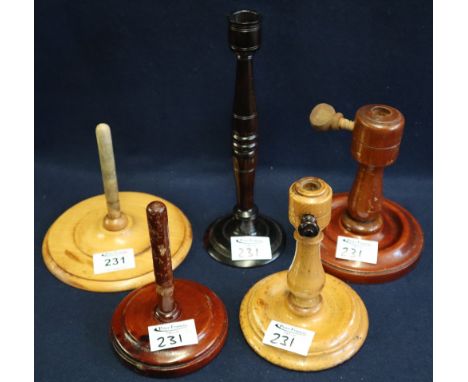 Treen. A group of three turned wooden craft stands, all with circular bases, together with a turned hardwood candle stick. (5