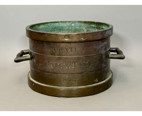 An early 19th century Irish bronze grain measure - of typical form with twin handles, one side inscribed 'County of Tipperary