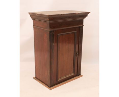 A small Edwardian mahogany cabinet - the moulded cornice over a panelled door flanked by fluted muntins, interior with single