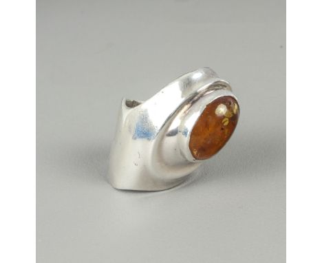 An unusual abstract-design white metal and amber ring - the oval cabochon amber set in an organic-style sleeve ring, unmarked