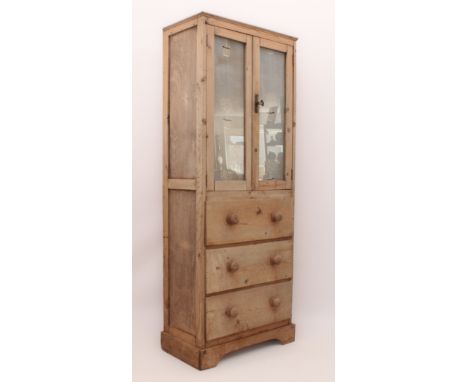 A stripped pine part-glazed cupboard on chest - early 20th century, the upper glazed doors enclosing an interior with two rem