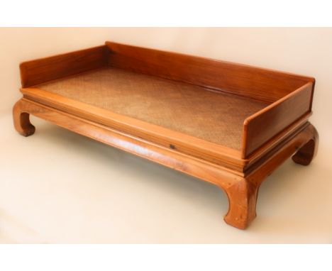 A Chinese Northern Elm opium bed - the rectangular top with rattan panel and removable three-quarter gallery, over a moulded 