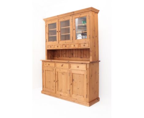 An antique-style pine dresser - the moulded cornice over three glazed doors enclosing a three-part interior, each section wit