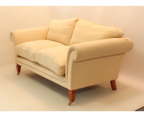 A two-seater sofa by David Linley - the slightly arched back over scroll arms and loose feather seat and back cushions in pla