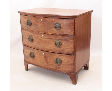 A Regency mahogany bow-fronted chest of drawers - with three long drawers with large circular brass handles (later) and ivory