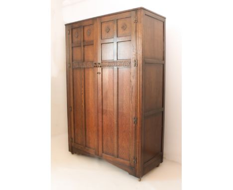 A mid-20th century carved oak wardrobe by Lawrencia Furniture - the six panel doors with carved foliate rosette and fruiting 