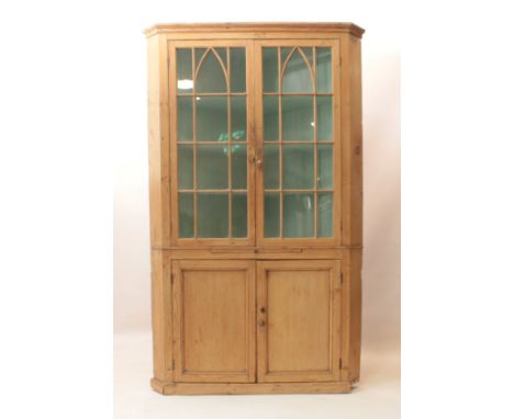 An early 19th century waxed pine floorstanding corner cupboard - the moulded cornice over a pair of 14-pane astragal glazed d