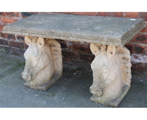 A modern concrete bench, the overhanging rectangular top raised on horse head supports, 56cm high, 104cm wide, 43cm deep.