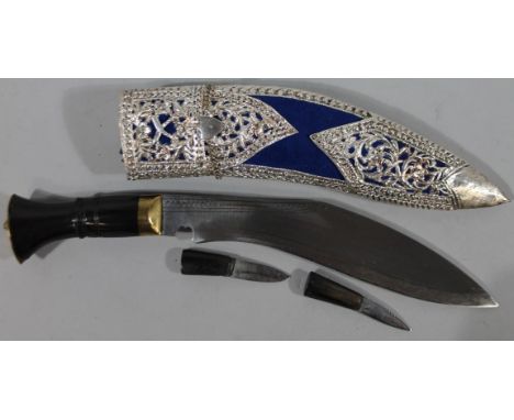 A 20thC Kukri knife, with elaborate shaped scabbard with silvered metal sections, a polished handle and brass coloured pommel