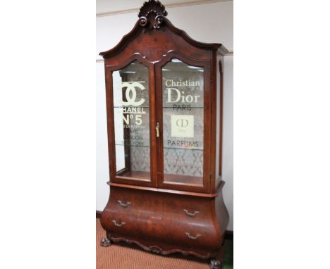 A 18thC style walnut stained bombé French display cabinet, the panelled doors stamped Chanel No 5 and Christian Dior Paris, s