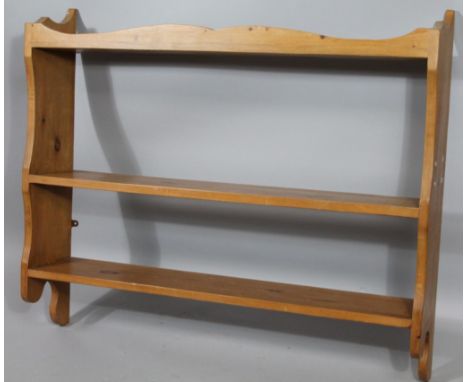 A 20thC stripped and lightly polished pine hanging shelf, with three sections, broken by shaped side supports with a carved f