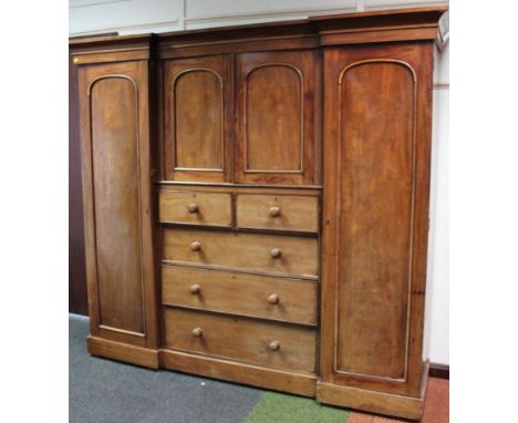 A Victorian mahogany triple sentry style wardrobe, the breakfront cornice raised above a pair of panelled doors and two short