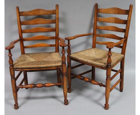 A pair of ash and elm rush seated dining chairs, with ladder back splat, shaped seats and turned front supports, terminating 