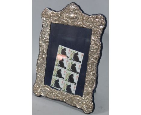An Elizabeth II silver photograph frame, heavily repoussé decorated with shaped rectangular form, raised with scrolls, with a