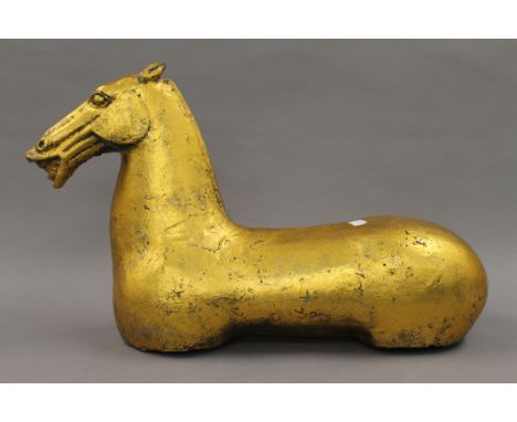 A golden coloured model of a horse. 31 cm high.