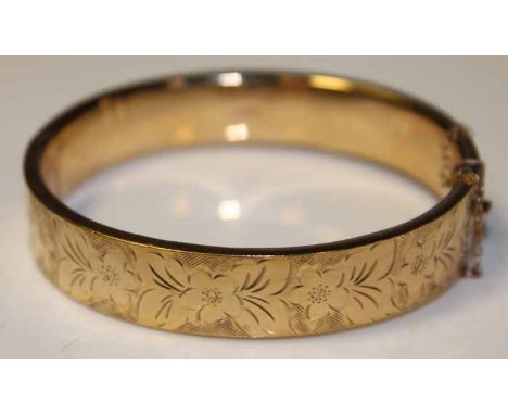 NINE CARAT GOLD BANGLE 
engraved with a floral design, 17.7g, 62mm diameter to inner edges, several dents to gold, otherwise 