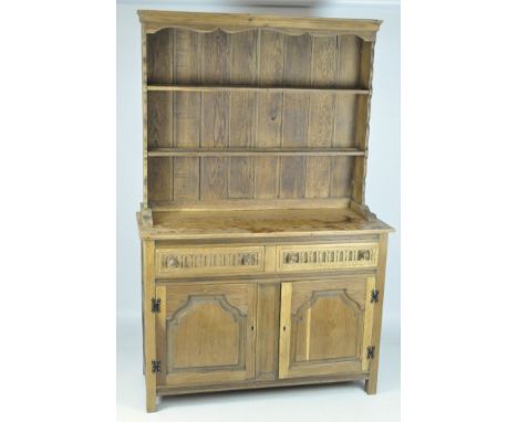 A stripped oak dresser, the upper section featuring a two shelf plate rack with a shaped edge, beneath a unit with hinged dou