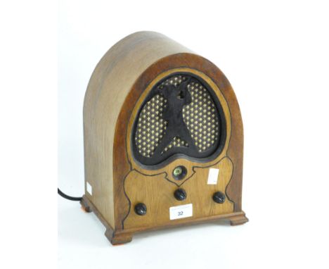 A vintage radio in stained wooden case with domed top, with silhouette of a trumpet playing figure, mains operated, 29cm high