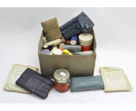 An assortment of vintage first aid equipment, including bandages and dressings, in original packaging