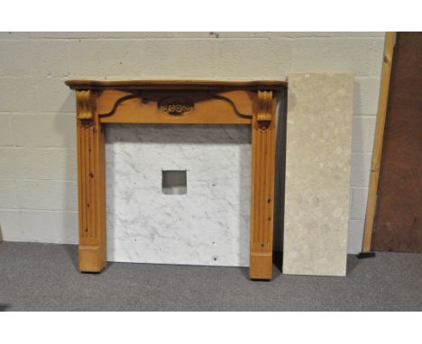 A modern pine fireplace surround, with reeded and bracket scroll uprights and mantlepiece, the centre carved with flowers, wi