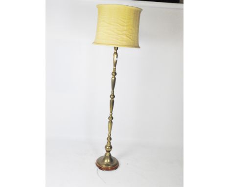 A 20th century standard lamp, the brass stand on a circular wooden base, with a yellow shade, height (excluding fitting) 149c