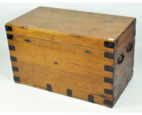 An early 20th century metal bound wooden trunk, with twin metal handles on each end, 61cm x 101cm x 55cm