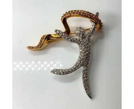 A pin depicting a person made of crystals holding up a golden plated banner decorated with golden crystals. This item has its