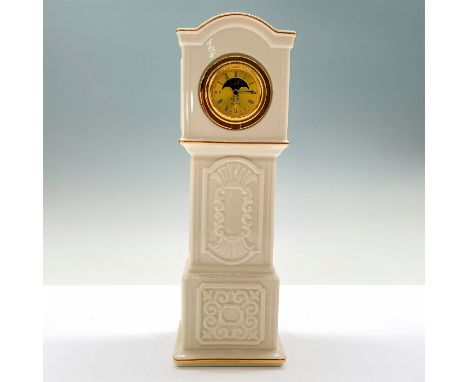 An off-white figurine of a ceramic patriarch clock with gold lining and a golden clock in the center. Lenox backstamp. This i