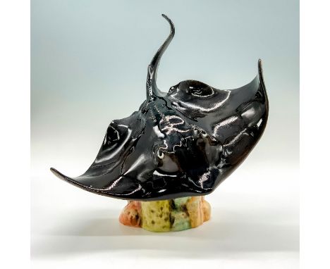 A figurine that depicts a black manta ray swimming over a coral reef with open wings. Goebel backstamp. Dimensions: 7"L x 6.7