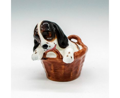 White and brown dog in basket, finished in light glaze. Royal Doulton backstamp. Issued: 1941-1985Dimensions: 3.5"L x 2"W x 2