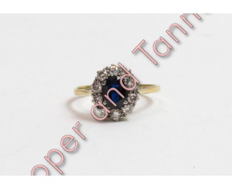 A sapphire and diamond cluster ring, stamped '18ct', the oval cut stone enclosed by ten brilliant cut diamonds totalling appr