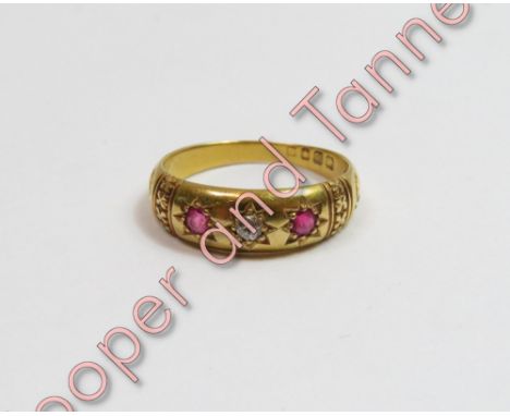 An Edwardian 18 carat gold ruby and diamond three stone ring, London 1903, with carved decoration to the head, finger size N,
