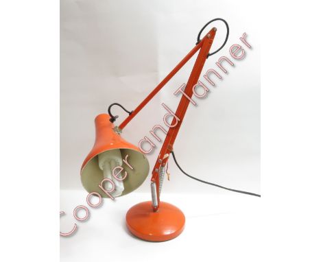 An orange painted metal angle poise lamp